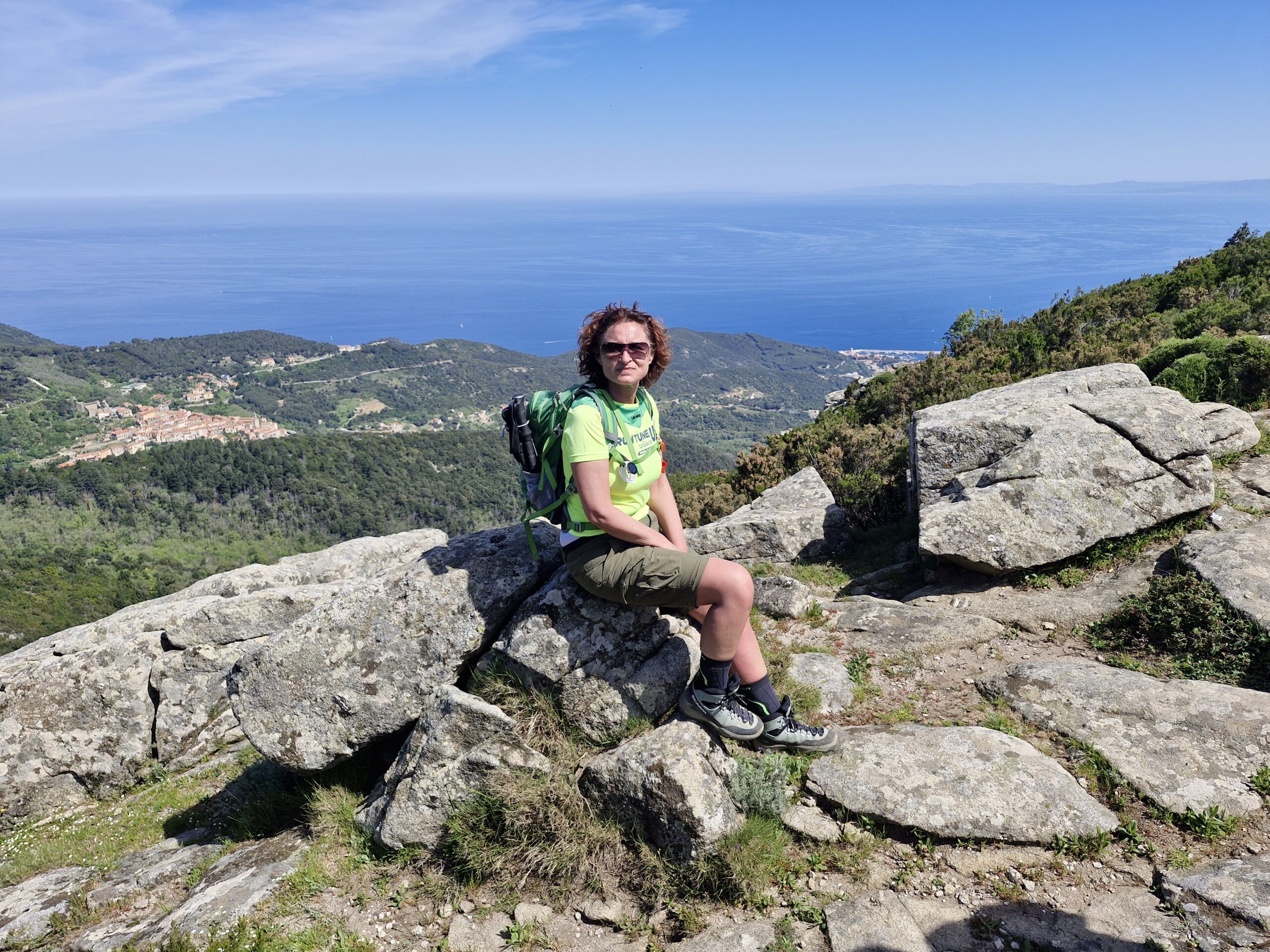 Donna trekker seduta su una roccia con vista panoramica su mare per i migliori consigli e percorsi di trekking